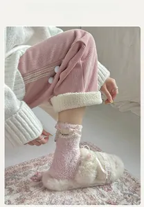 Detail of coral fleece socks with pink ribbon bows and faux pearls near plush slippers