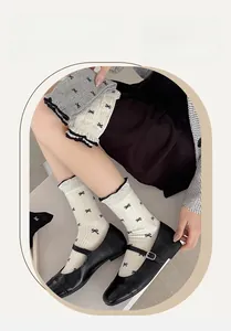 Close-up of cotton crew socks featuring black bow patterns and elegant ruffled edges