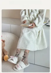 Close-up of cozy bear fuzzy socks and white plush slippers with a pink bow detail