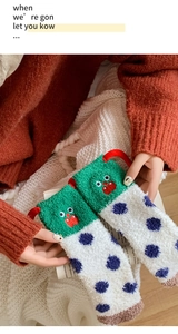 Detailed view of thick coral fleece socks with cartoon monster embroidery and polka dots