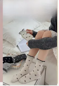 Detail of grey slouch socks featuring bow patterns and black ruffled lettuce edge cuffs