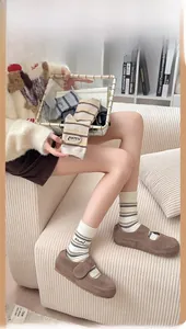 Detail of striped crew socks with 'As You Wish' embroidery and brown Mary Jane shoes
