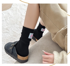 Close-up of black wool socks with cute cartoon patch and grey felt buckle clogs