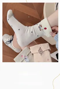 Detail of embroidered cartoon puppy on ribbed knit crew socks with polka dot pattern