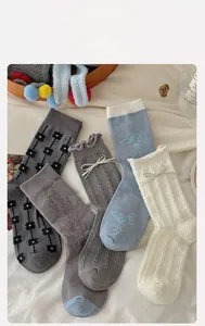 Close-up of assorted cotton socks with bow and floral embroidery in soft grey tones