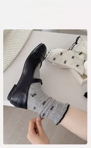 Close-up of knit crew socks featuring black bow prints and elastic ruffled cuffs