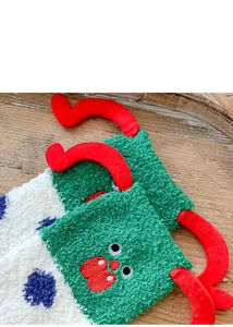 Close-up of thick coral fleece Christmas socks with festive elk antlers and cartoon details