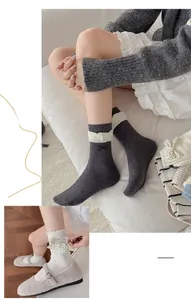 Detail of white mid-calf socks with polka dot bow and grey cross-stitch socks