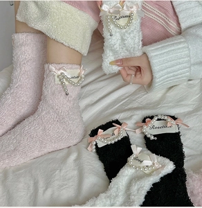 Detail of coral fleece socks featuring pearl charms and pink ribbon bows in three colors