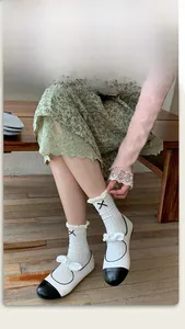 Detail of white ruffle socks with black cross embroidery and Mary Jane bow shoes