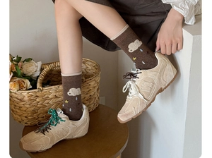 Detail of cartoon cloud socks paired with suede sneakers for a cozy autumn look