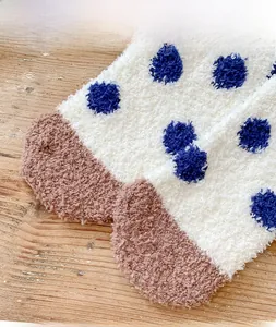 Close-up of thick coral fleece winter socks with blue polka dots on warm wooden background