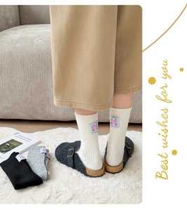 Detailed knit texture of wool socks featuring a cartoon elephant patch on the ankle cuff