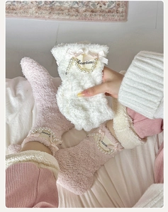 Detail of coral fleece socks featuring pearl chains, ribbon bows, and logo labels