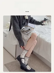 Close-up of white crew socks with black bow patterns and elegant wavy ruffle cuffs