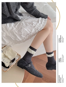 Detail of dark grey knit mid-calf socks with white ruffled lace and bow embroidery
