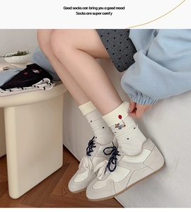Detail of cream dog embroidery socks with yellow fold-over cuffs and black polka dots