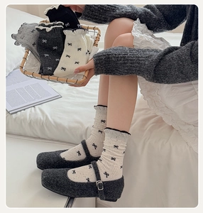 Detail of ruffled cuff socks with bow patterns paired with grey Mary Jane shoes