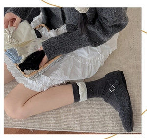 Close-up of knit crew socks featuring elegant ruffles and bow accents in neutral tones