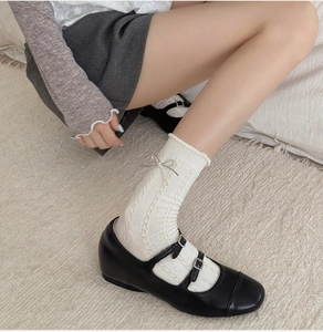 Detail of white cotton crew socks with knit patterns and silk ribbon bows on the side