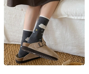 Detail of beige suede clogs with bronze buckle and cute cloud pattern knit socks