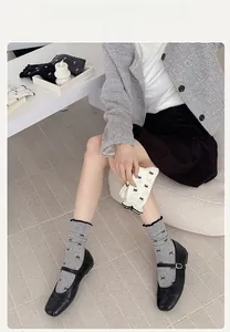 Detail of grey crew socks with black bow patterns and ruffled trim for a stylish look