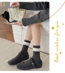 Detail of dark grey knit socks with cream ruffled trim paired with Mary Jane shoes