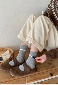 Détail de chaussettes mi-mollet grises avec nœud noir et accents de rayures blanches