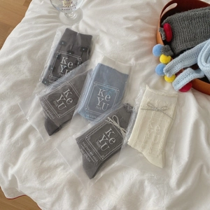 Set of grey and cream cotton crew socks with floral embroidery on white fabric
