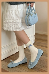 Detailed shot of navy blue cable-knit socks with plaid bows and light blue ballet flats