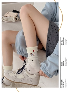 Close-up of cream crew socks featuring dog embroidery and stylish black polka dots