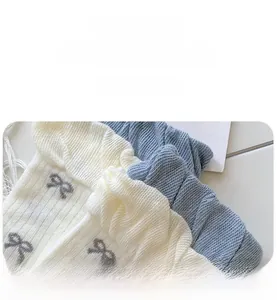 Detail of ballet style knit socks with bow jacquard and ruffled cuffs in cream and blue