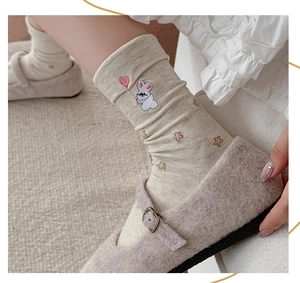 Close-up of beige crew socks with pink heart and rabbit embroidery for a cute style