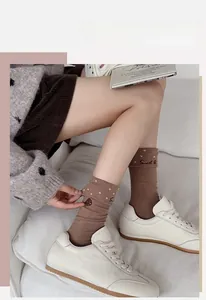 Détail de chaussettes en coton marron café avec pois roses et broderie de gâteau doux