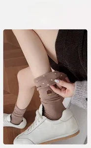 Détail de chaussettes en maille marron avec pois blancs et broderie cupcake élégante