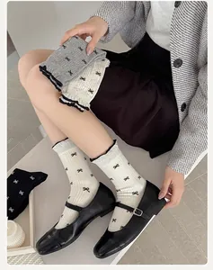Detail of ribbed crew socks with black bow prints and elegant ruffled cuffs for women