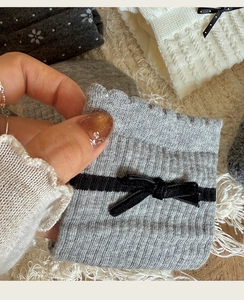 Detail of grey striped knit socks with black bows and floral lace patterns for women