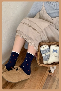 Detail of navy blue floral socks and cream bow socks with elegant ruffled cuffs