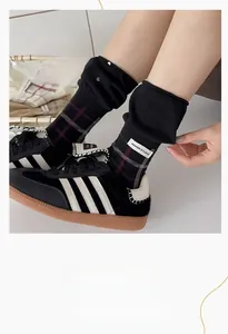 Close-up of black plaid crew socks with elastic cuff and signature fabric label detail