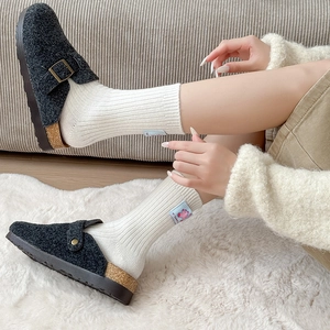 Women's black felt mule slippers with adjustable buckle on cozy white wool socks