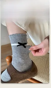 Détail de chaussettes grises avec revers côtelés élastiques et nœuds noirs décoratifs