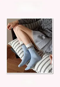 Detail of light blue crew socks with white heart embroidery and wavy layered cuffs