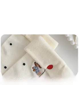 Detailed macro view of cream knitted sock with polka dots and cute dog embroidery detail