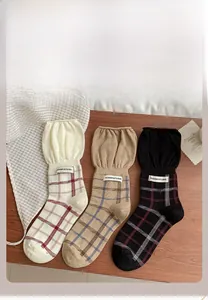 Close-up of three pairs of vintage plaid cotton socks with ruffled cuffs on wooden background