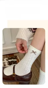 Close-up of white knit socks with lace patterns and a brown bow detail