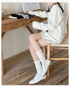 Detail of white slouch socks with pleated texture and floral accents with flat shoes