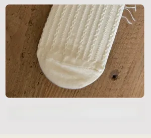 Close-up of white ribbed knit cotton socks showing the flat toe seam on a wooden background