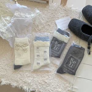 Pack of four stylish bow and polka dot crew socks displayed on a soft plush white blanket
