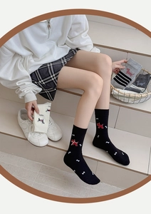 Close-up of knit mid-tube socks featuring cute puppy and bone patterns on models