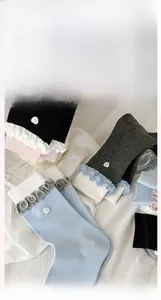 Detail showing wavy ruffled cuffs with a delicate white heart button on cotton socks